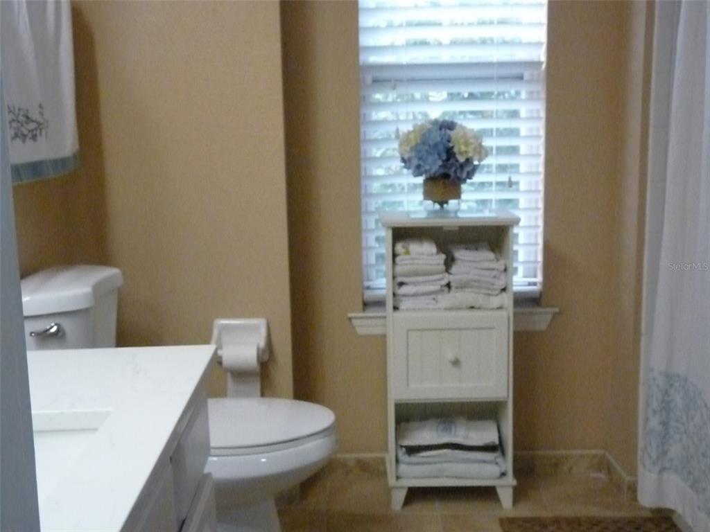A bathroom features a white vanity, a toilet, and a tiered storage shelf by the window — 400 SUMMIT RIDGE PLACE UNIT 216, LONGWOOD, FL