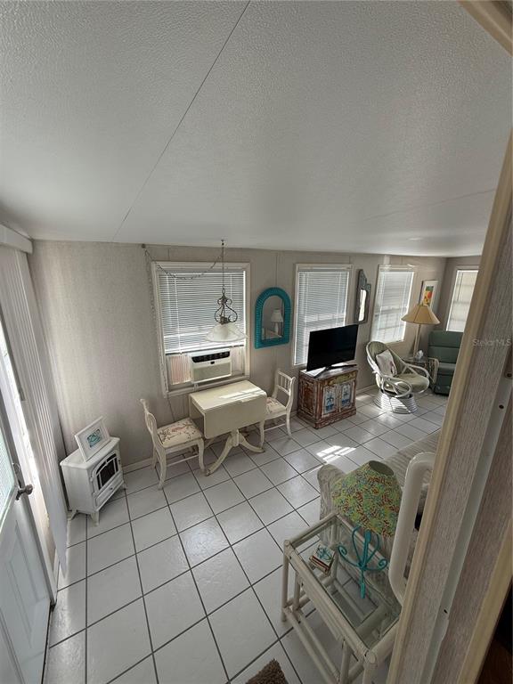 A sunroom features white tile floors, a small dining set, and a television on a cabinet — 1475 FLAMINGO DRIVE UNIT 117, ENGLEWOOD, FL