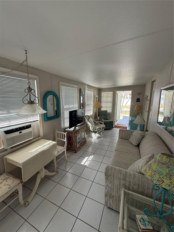 A sunroom features tile flooring, a dining table, a sofa, and a window air conditioner — 1475 FLAMINGO DRIVE UNIT 117, ENGLEWOOD, FL