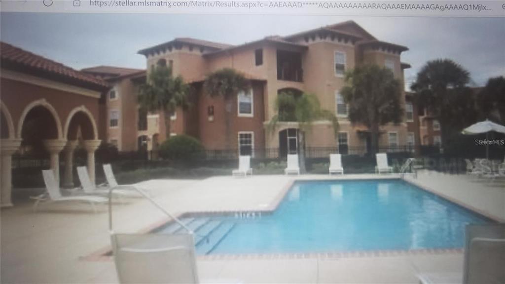 A swimming pool sits in front of a multi-story apartment building with Mediterranean-style architecture — 5566 METROWEST BOULEVARD UNIT 306, ORLANDO, FL