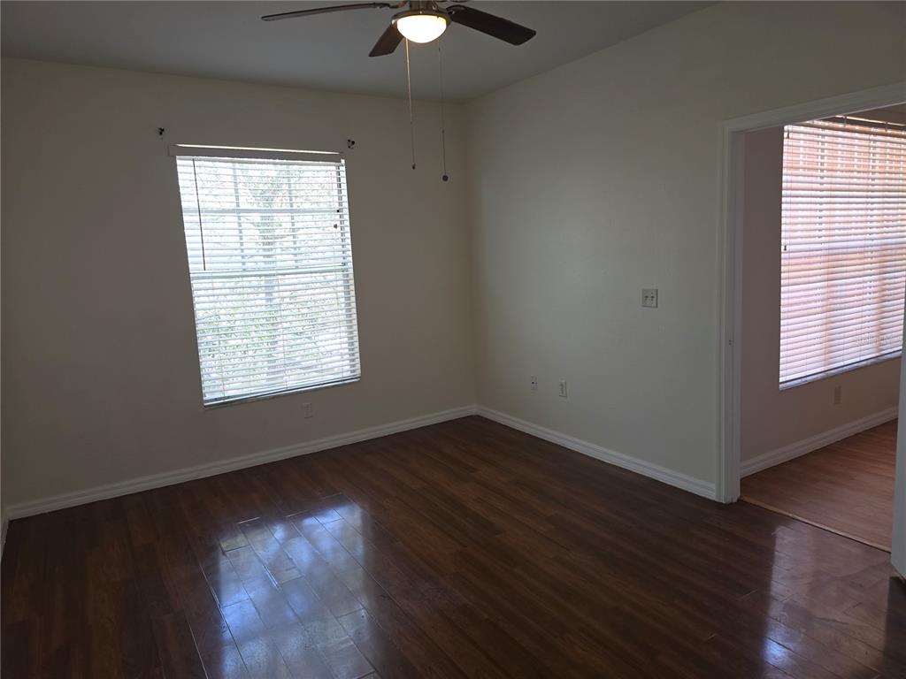 An empty room with dark wood flooring, a ceiling fan, and a window with blinds — 5566 METROWEST BOULEVARD UNIT 306, ORLANDO, FL