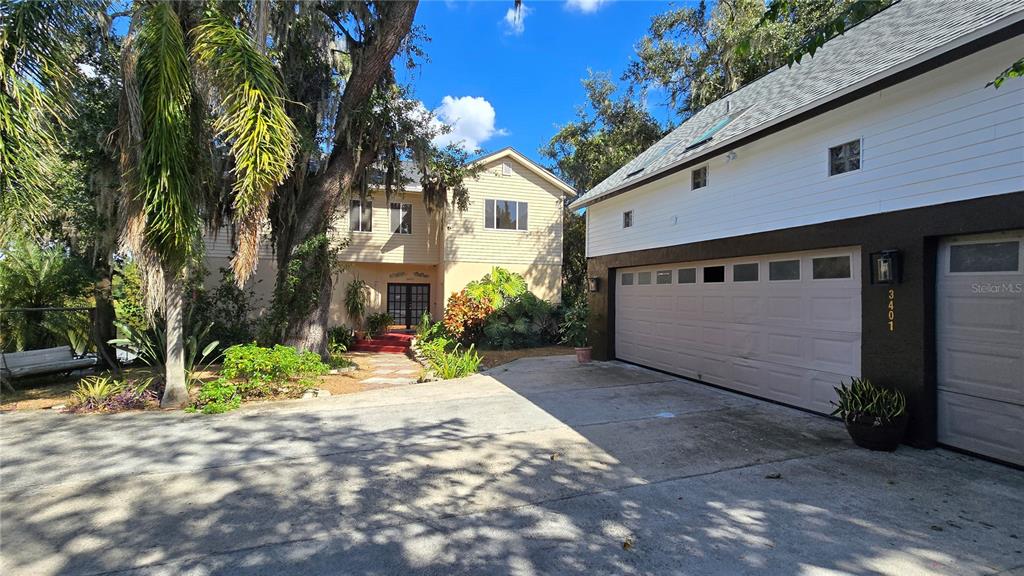 A two-story house with a detached garage sits behind a large paved driveway — 3401 E SLIGH AVENUE, TAMPA, FL