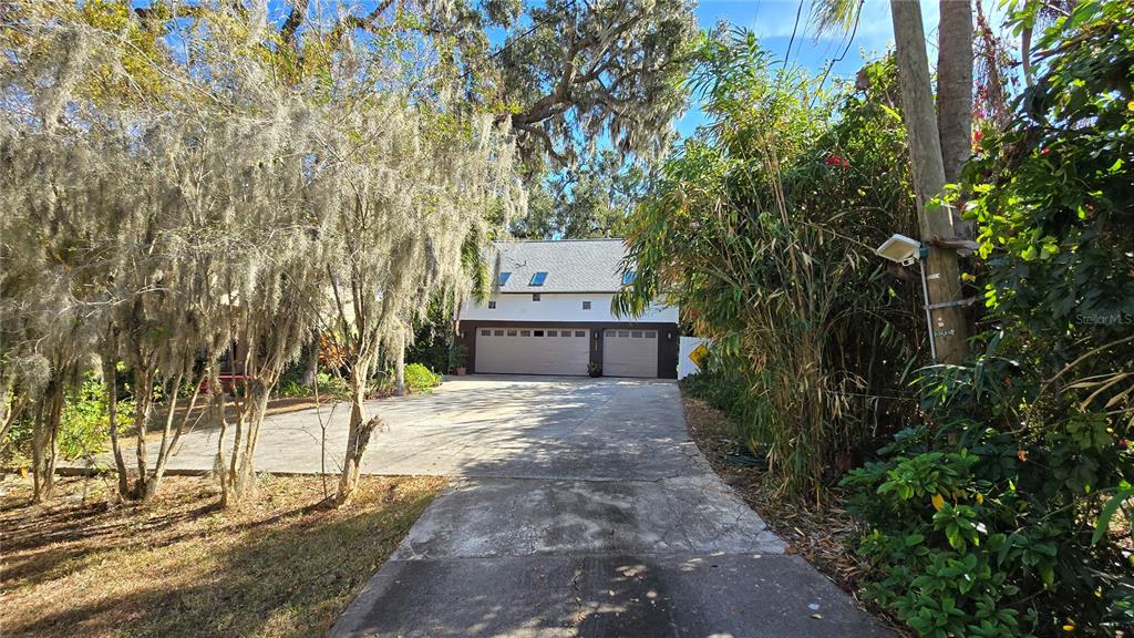 A concrete driveway leads to a two-car garage with a finished living space above — 3401 E SLIGH AVENUE, TAMPA, FL