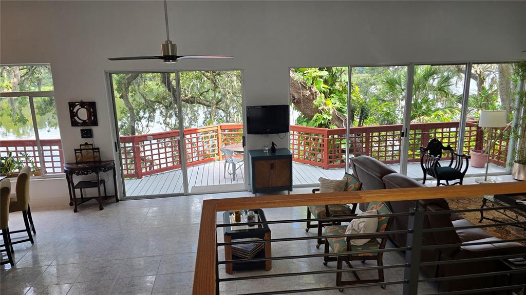 A living room with tile floors, a ceiling fan, and sliding glass doors overlooking a deck — 3401 E SLIGH AVENUE, TAMPA, FL