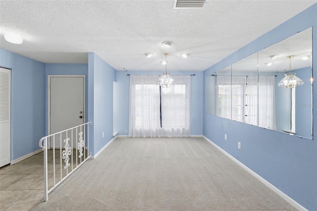 A dining room with light blue walls, carpeted flooring, a chandelier, and a large wall mirror — 8307 VALLEJO PLACE, TAMPA, FL