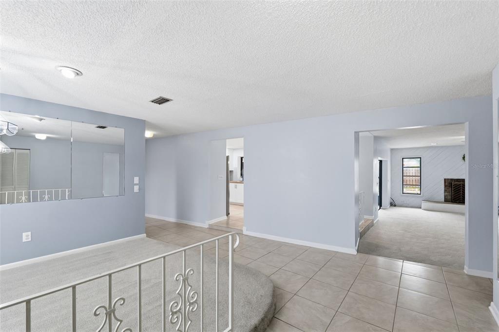 An interior view shows a tiled entryway, a carpeted living area, and a mirrored wall — 8307 VALLEJO PLACE, TAMPA, FL