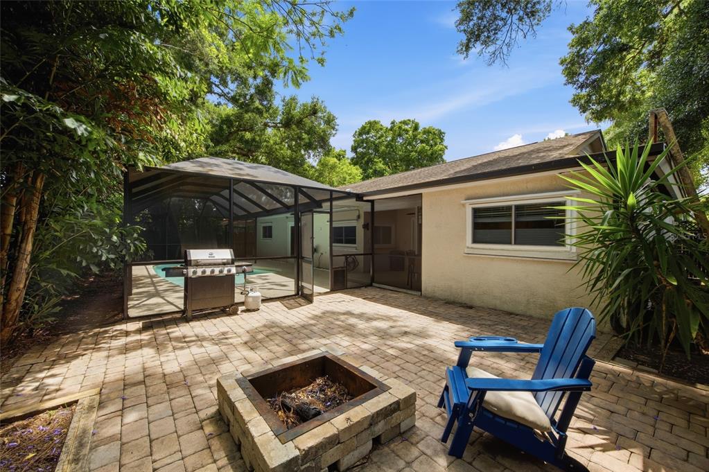 A swimming pool with a screened-in enclosure sits behind a house with a stucco exterior — 2447 GROVE RIDGE DRIVE, PALM HARBOR, FL