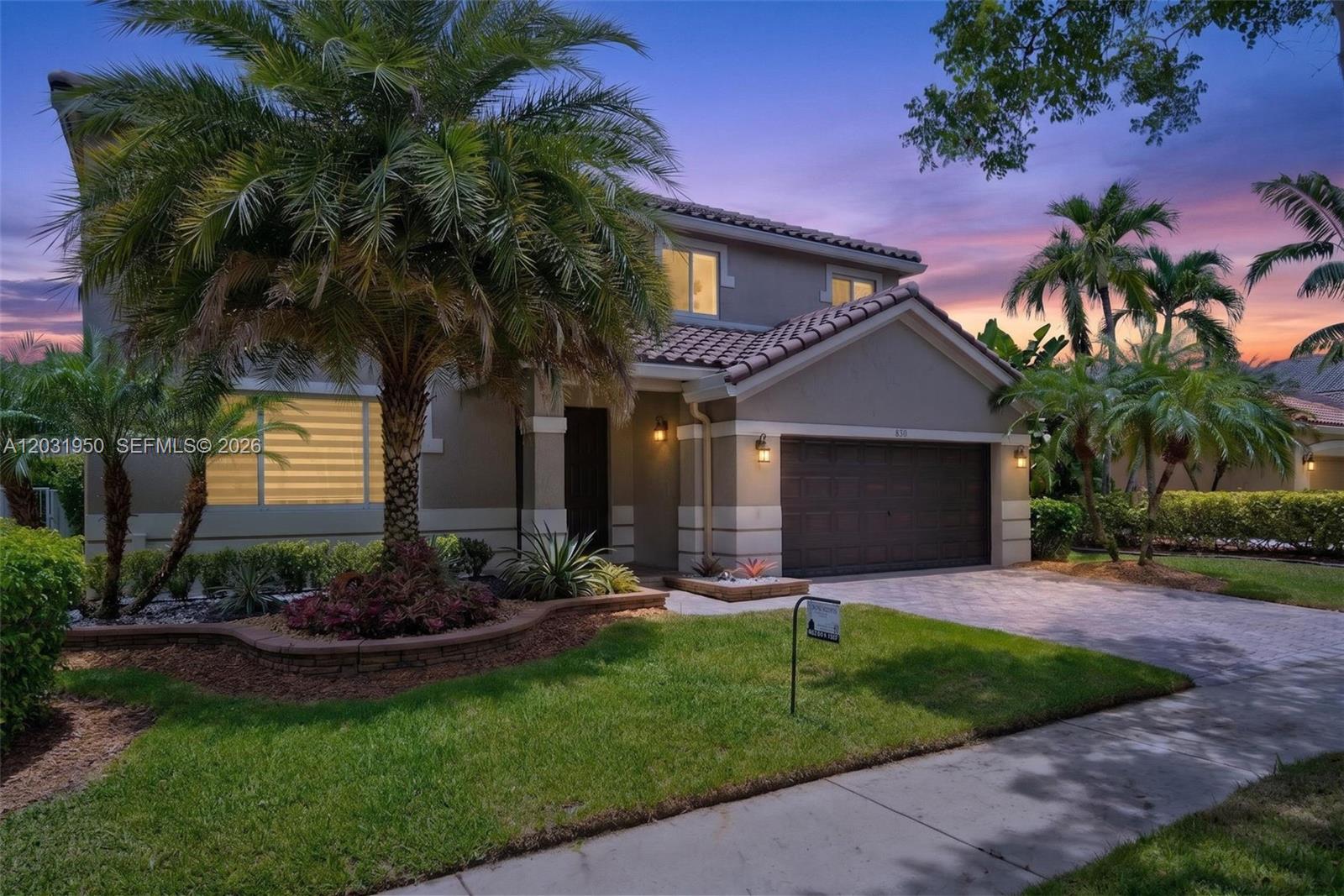 A two-story house with a tile roof, a two-car garage, and palm trees at dusk — 830 Hawthorn Ter, Weston FL 33327, WESTON, FL