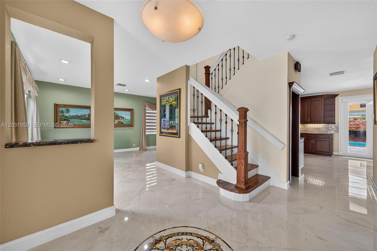 A foyer features a staircase with iron railings, light tile floors, and a pass-through window — 830 Hawthorn Ter, Weston FL 33327, WESTON, FL