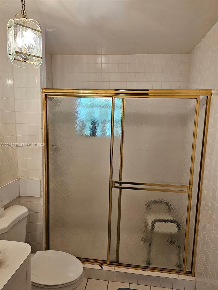 A bathroom features a glass shower enclosure with gold trim and white tiled walls — 9905 Marlin RD # 0, Cutler Bay FL 33157, CUTLER BAY, FL