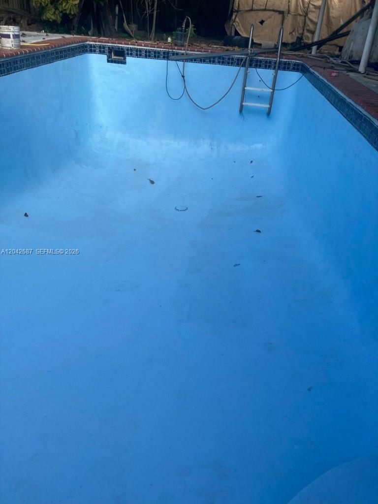 An empty, light blue swimming pool with a metal ladder and brick coping — 9905 Marlin RD # 0, Cutler Bay FL 33157, CUTLER BAY, FL