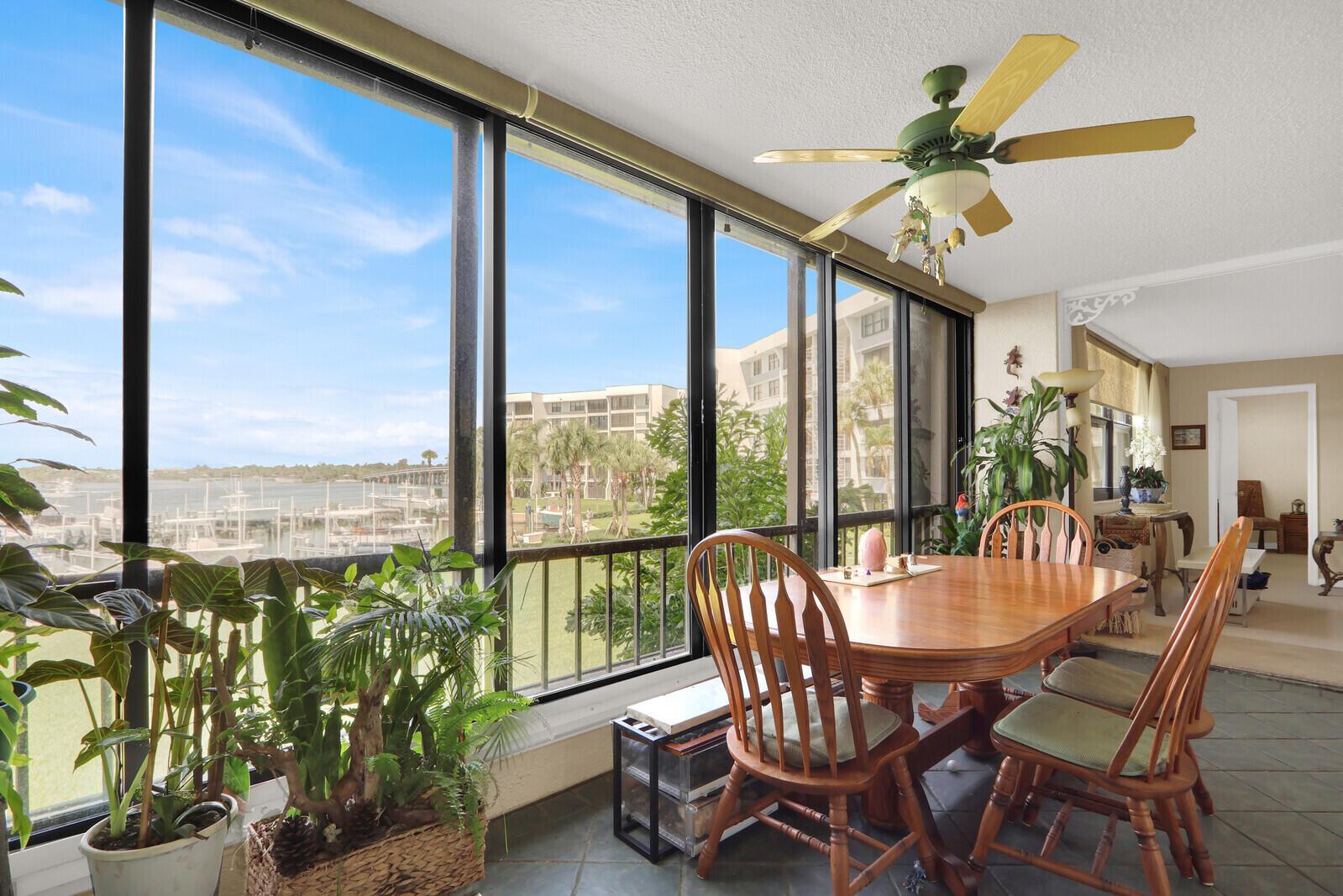 A sunroom with a dining table, ceiling fan, and large windows overlooking a marina — 1648 Jupiter Cove Drive # 214, Jupiter FL 33469, JUPITER, FL