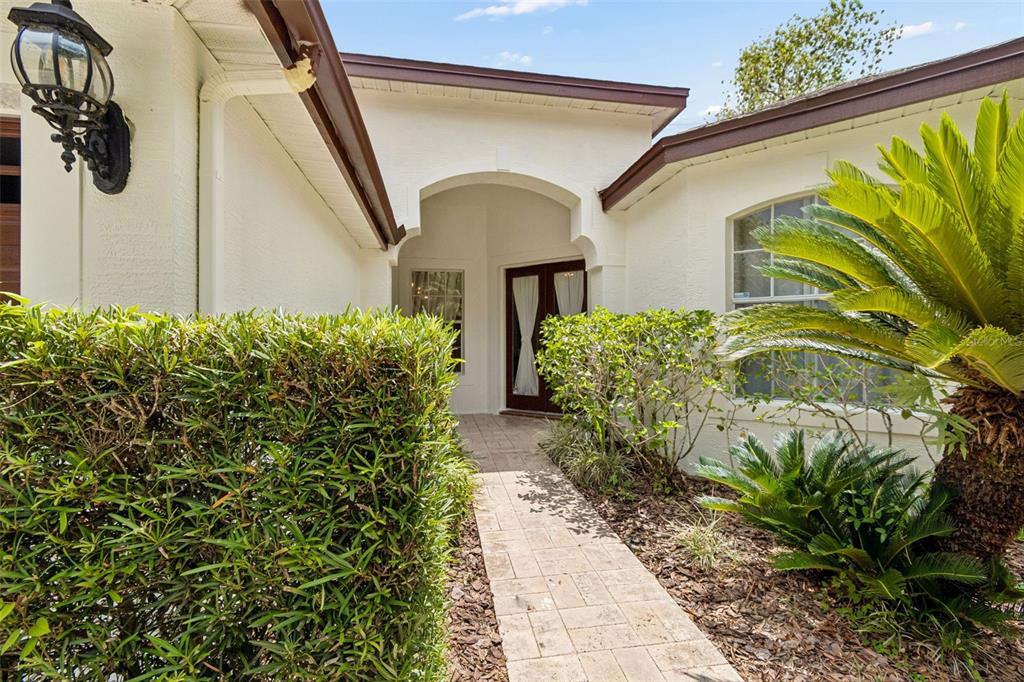 A stone walkway leads to the front entrance of a house with white stucco walls — 10502 CASTLEFORD WAY, TAMPA, FL
