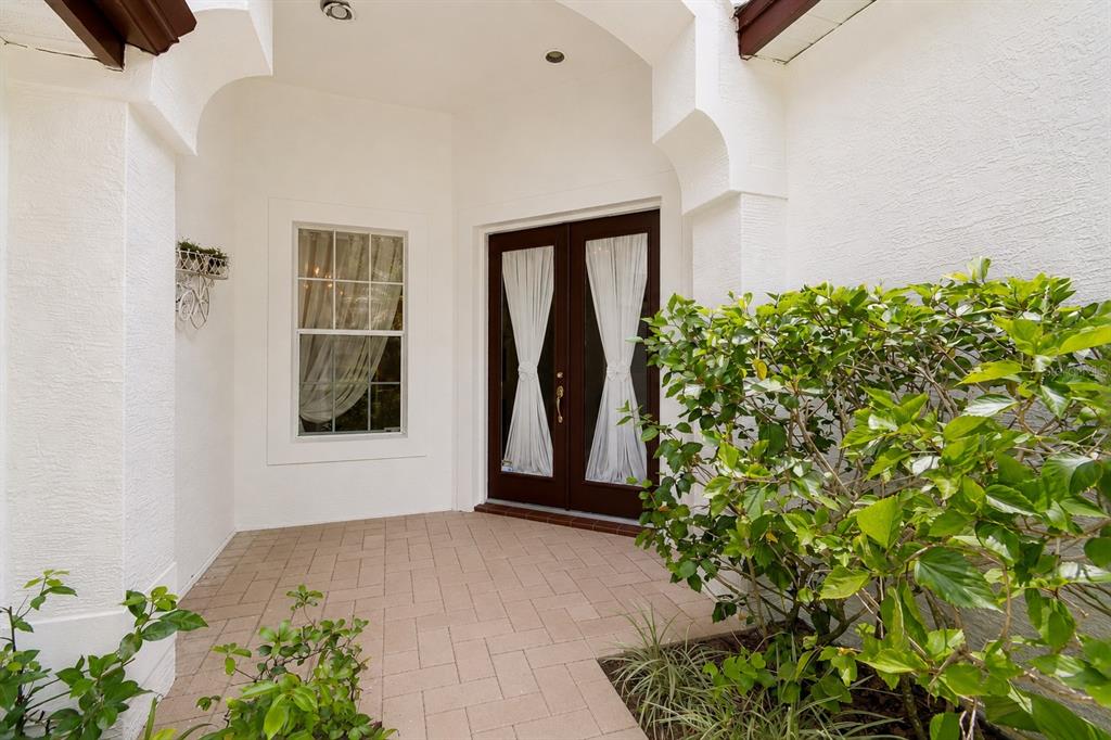 A covered entryway features a paved floor, a double front door, and a side window — 10502 CASTLEFORD WAY, TAMPA, FL
