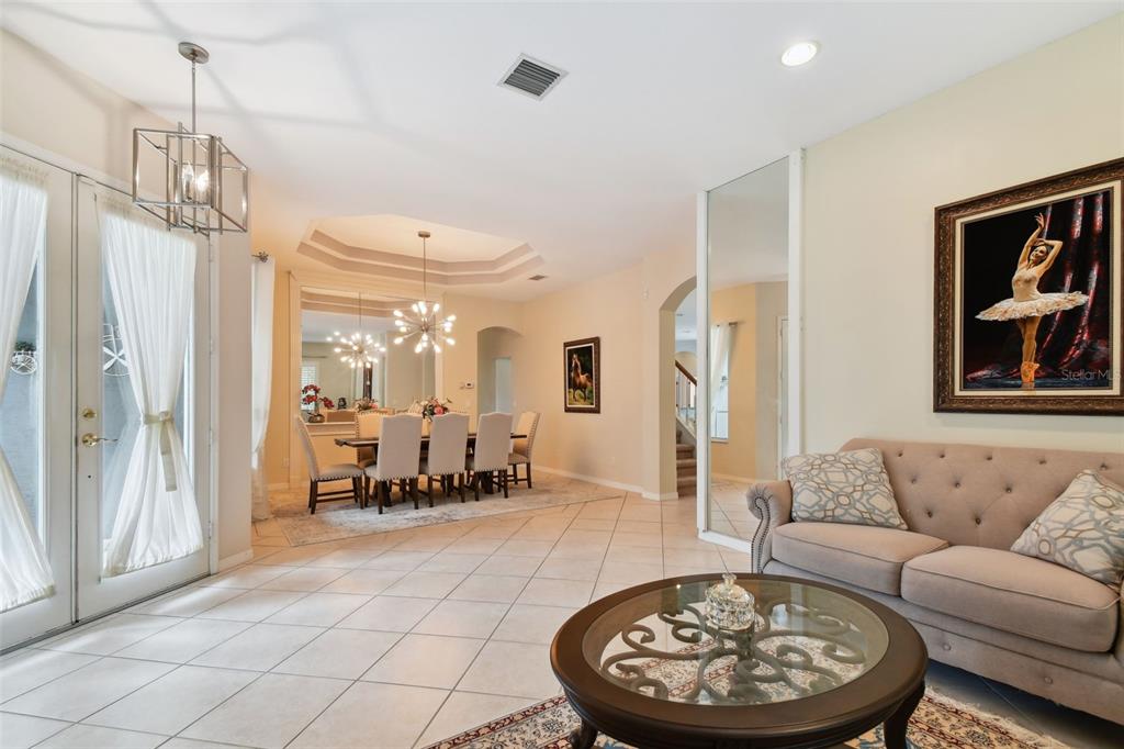 A living room with tile floors, a beige sofa, and a dining area in the background — 10502 CASTLEFORD WAY, TAMPA, FL