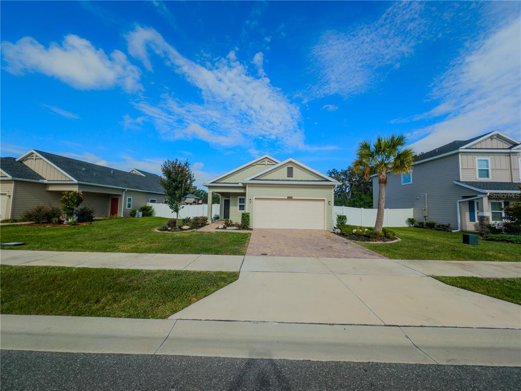 A single-story light green house with a two-car garage and a paved driveway — 2022 NW 44TH COURT ROAD, OCALA, FL