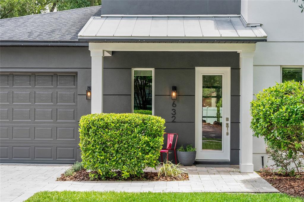 A modern home exterior features a gray facade, white door, metal roof, and manicured landscaping — 632 GAMEWELL AVENUE, MAITLAND, FL