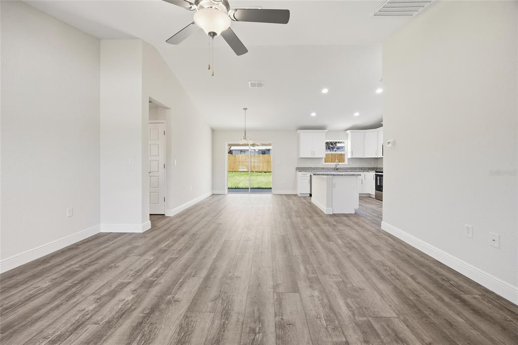 An open-concept living area with wood-look flooring, a ceiling fan, and an adjacent kitchen — 6762 W CHERRY ROAD, OCALA, FL
