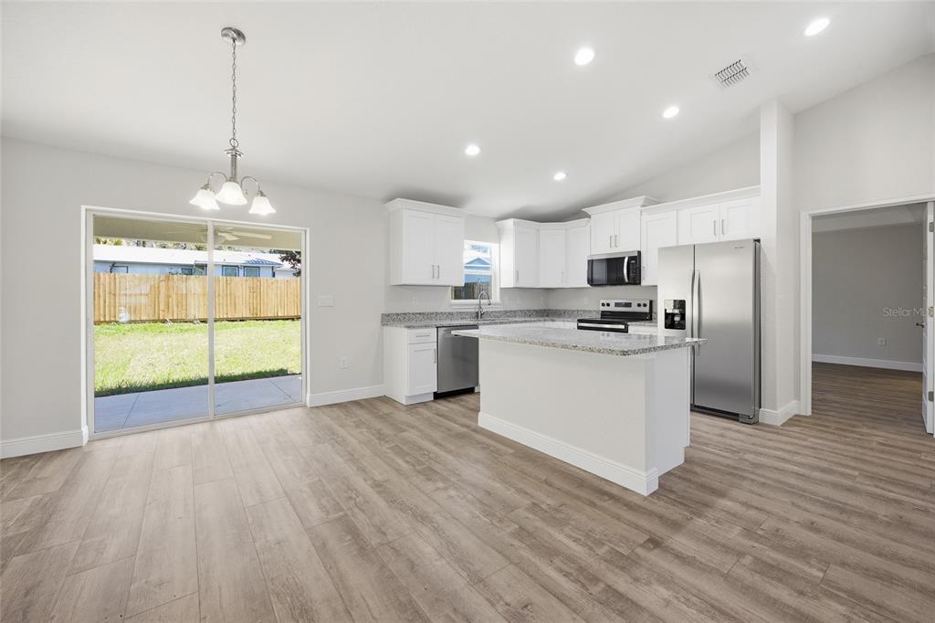 A kitchen with white cabinets, granite countertops, stainless steel appliances, and wood-look flooring — 6762 W CHERRY ROAD, OCALA, FL