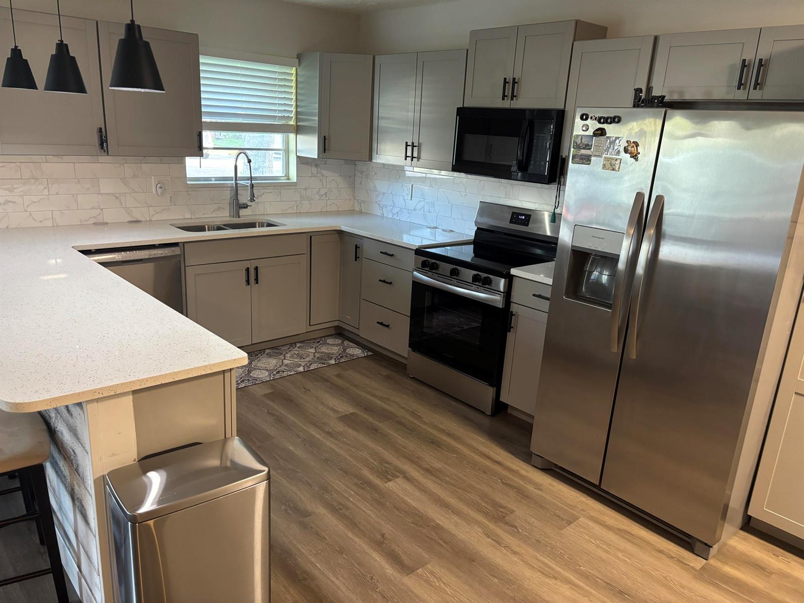 A modern kitchen features gray cabinets, stainless steel appliances, and white marble-patterned countertops — 211 Country Lane # C, Boynton Beach FL 33435, BOYNTON BEACH, FL