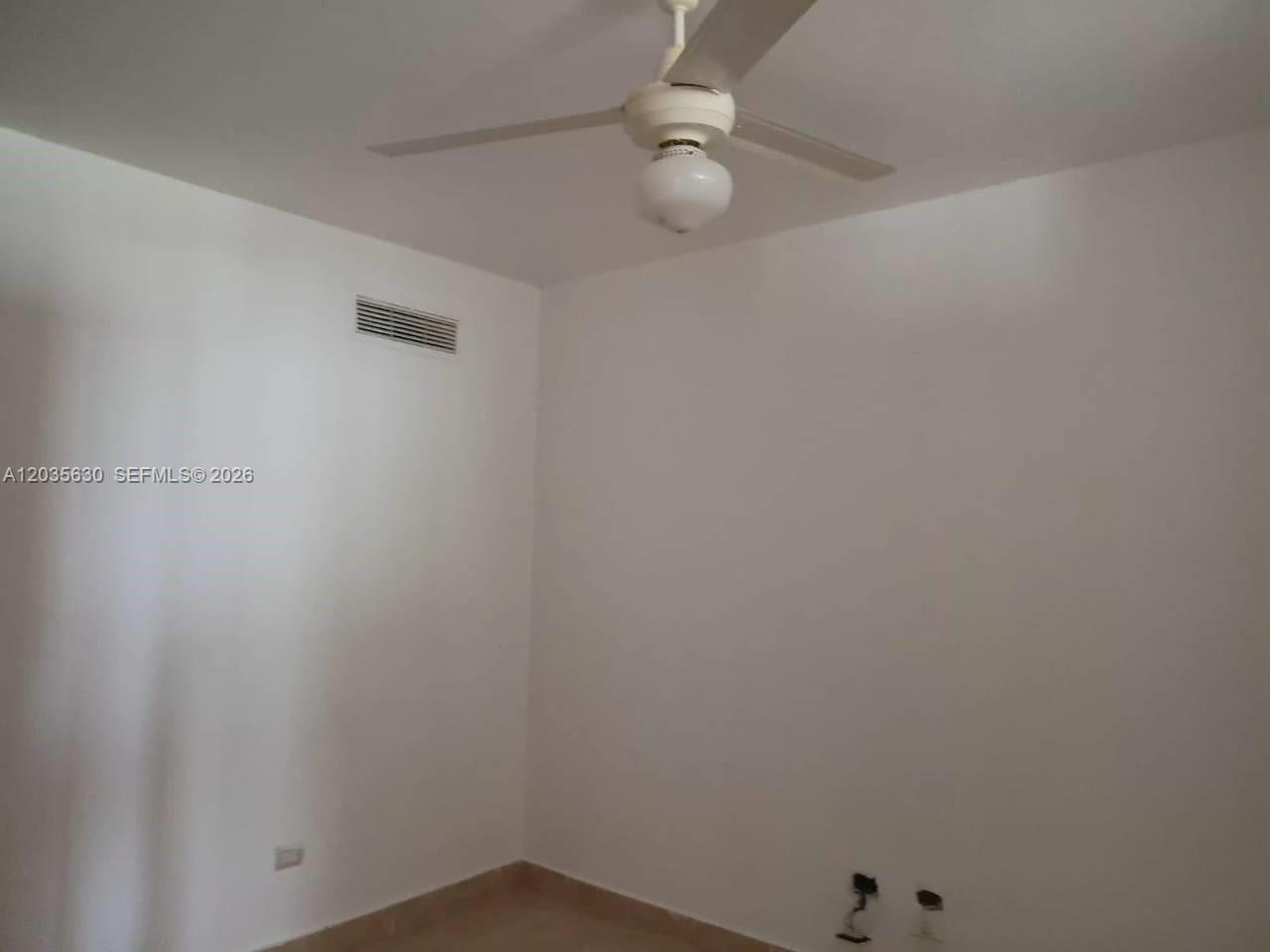 An empty room features white walls, a ceiling fan with a light, and tile flooring — 1 cap cana # 0, FL