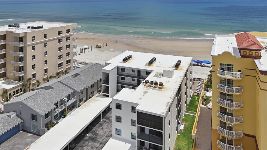An aerial view shows several multi-story beachfront apartment buildings near a sandy beach and ocean — 3807 S ATLANTIC AVENUE UNIT 4040, DAYTONA BEACH SHORES, FL