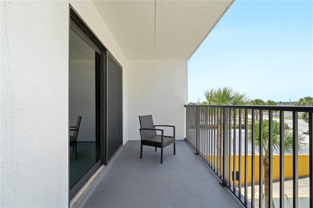 A balcony with a single chair, sliding glass doors, and a black metal railing — 3807 S ATLANTIC AVENUE UNIT 4040, DAYTONA BEACH SHORES, FL