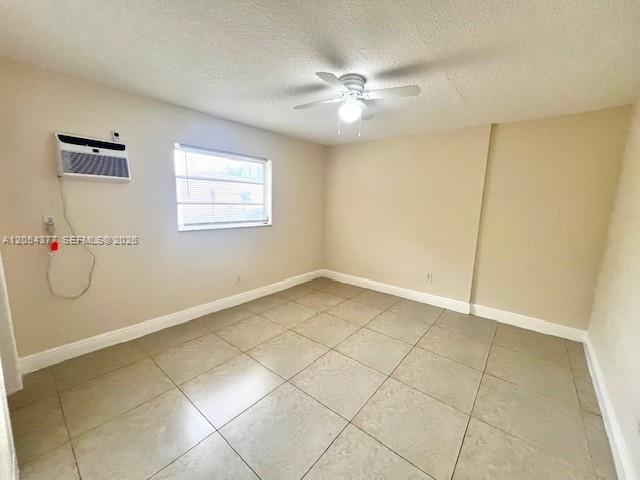 An empty room features beige walls, light-colored tile flooring, a ceiling fan, and a window unit — 685 NE 85th St # 2, Miami FL 33138, MIAMI, FL