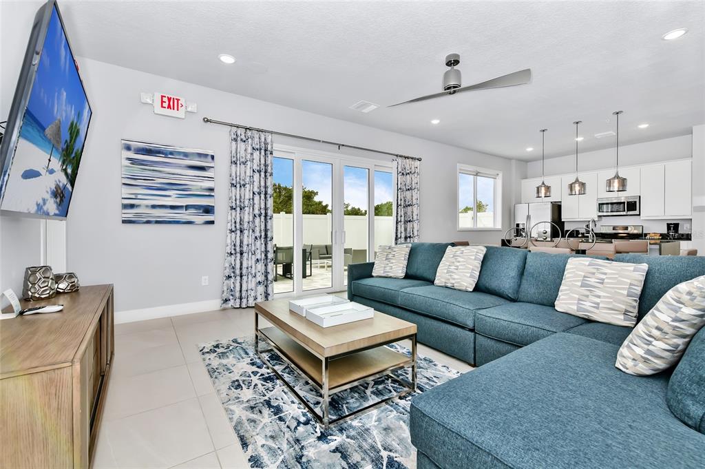 A living room with a blue sectional sofa, coffee table, and an open kitchen — 7770 SANDY RIDGE DRIVE UNIT 108, KISSIMMEE, FL