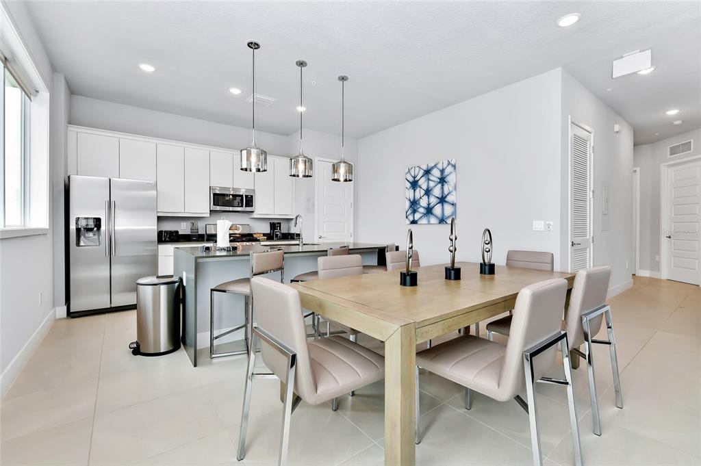 A modern kitchen and dining area with white cabinets, stainless steel appliances, and tile flooring — 7770 SANDY RIDGE DRIVE UNIT 108, KISSIMMEE, FL