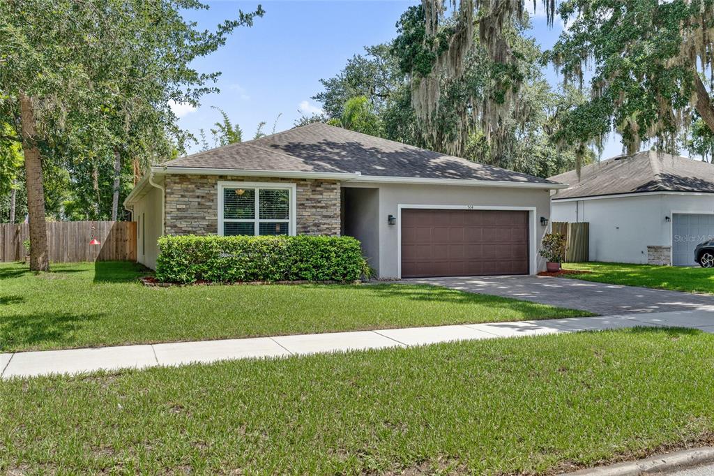 A single-story house with a stone facade, a two-car garage, and a manicured front lawn — 504 E 14TH STREET, SANFORD, FL