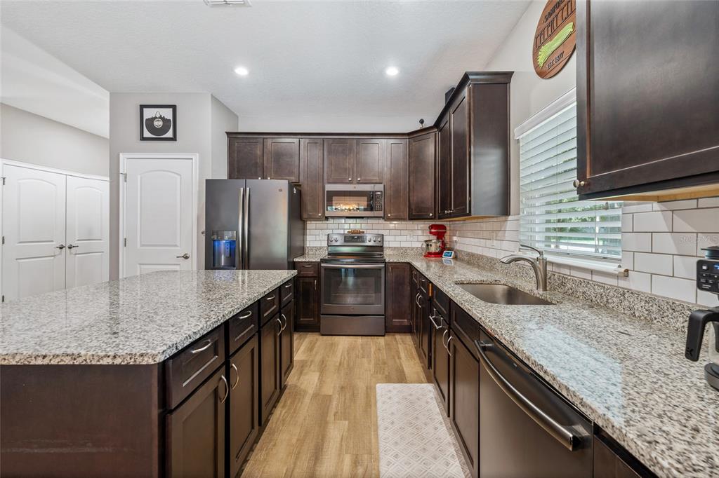 A kitchen features dark wood cabinets, granite countertops, stainless steel appliances, and a central island — 504 E 14TH STREET, SANFORD, FL