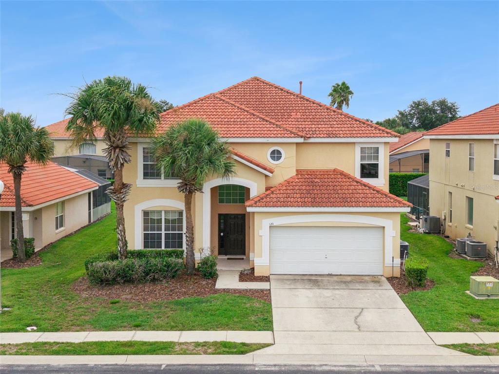 A two-story stucco house with a red tile roof and a two-car garage — 120 SARAGOSSA AVENUE, DAVENPORT, FL