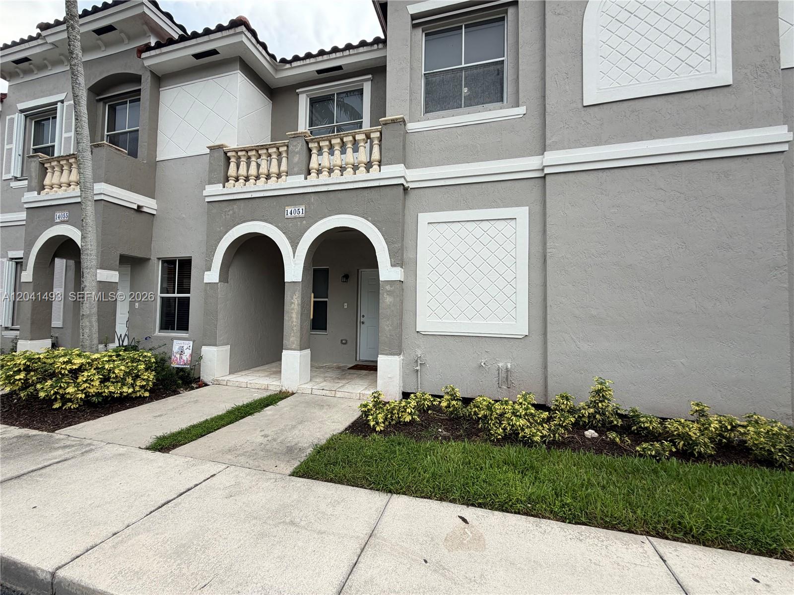 A two-story townhouse exterior features gray stucco walls, arched entryways, and a second-floor balcony — 14051 SW 49th Ct # 7, Miramar FL 33027, MIRAMAR, FL