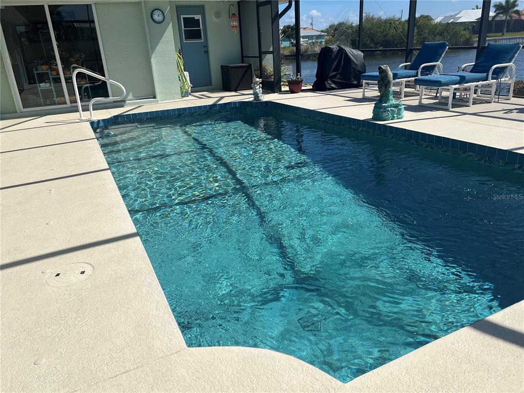 A rectangular swimming pool sits on a concrete deck inside a screened-in lanai — 9458 MELODY CIRCLE, PORT CHARLOTTE, FL