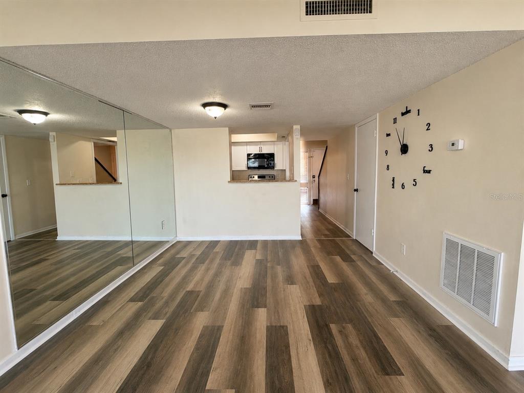 A dining area features wood-look flooring, a mirrored wall, and a wall-mounted clock — 5967 WINDHOVER DRIVE UNIT 7D, ORLANDO, FL