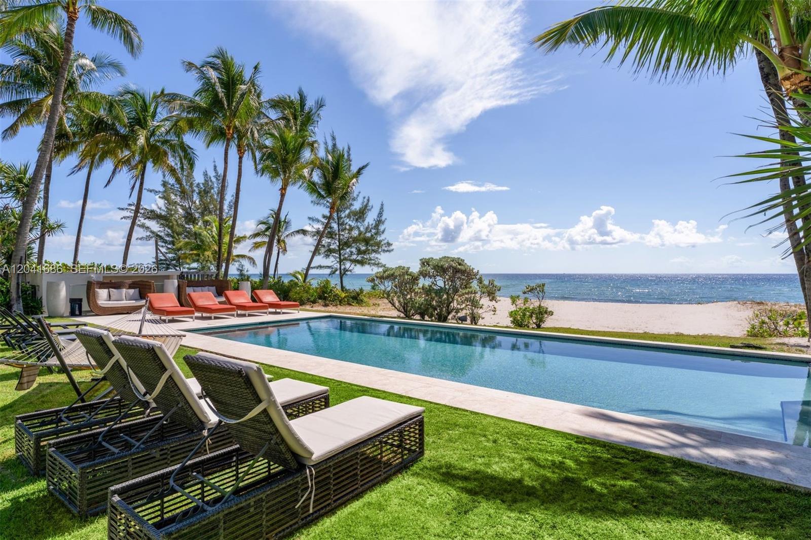 A rectangular swimming pool sits on a grassy lawn overlooking a sandy beach and ocean — 115 Ocean Blvd, Golden Beach FL 33160, GOLDEN BEACH, FL