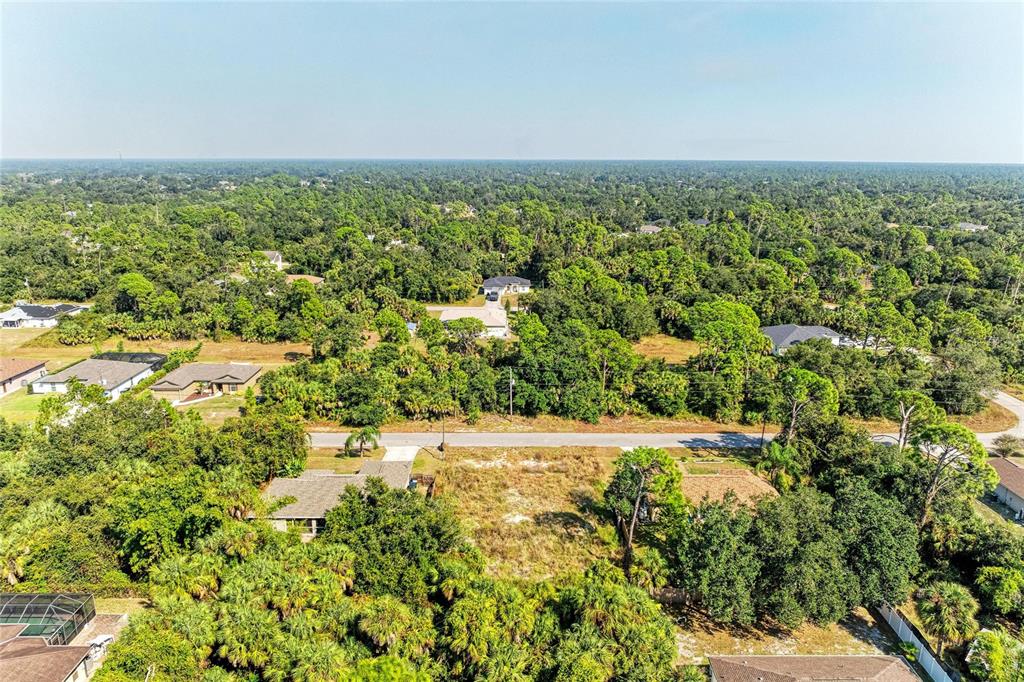 An aerial view shows a vacant residential lot surrounded by trees and neighboring houses — 4263 GALVIN LANE, NORTH PORT, FL