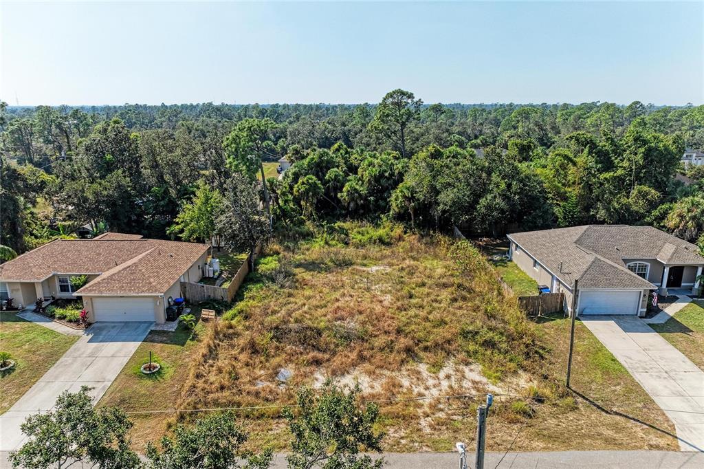 An aerial view shows a vacant, grassy residential lot situated between two single-family homes — 4263 GALVIN LANE, NORTH PORT, FL