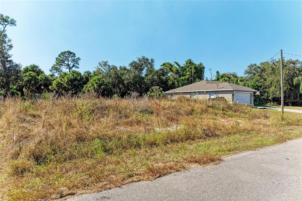 A vacant, overgrown lot sits next to a single-story house with a garage — 4263 GALVIN LANE, NORTH PORT, FL