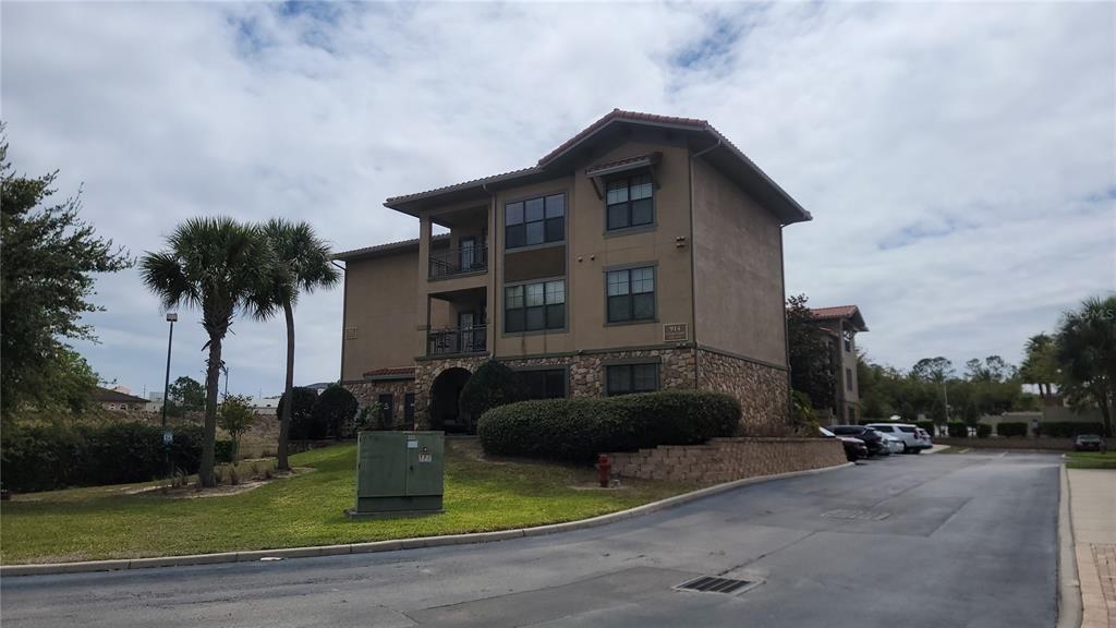 A three-story apartment building with a stone facade, balconies, and a paved driveway — 914 CHARO PARKWAY UNIT 123, DAVENPORT, FL