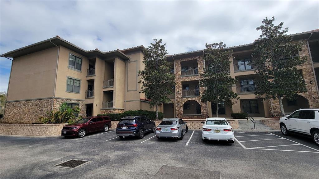 A three-story apartment building with stone accents and a parking lot in front — 914 CHARO PARKWAY UNIT 123, DAVENPORT, FL