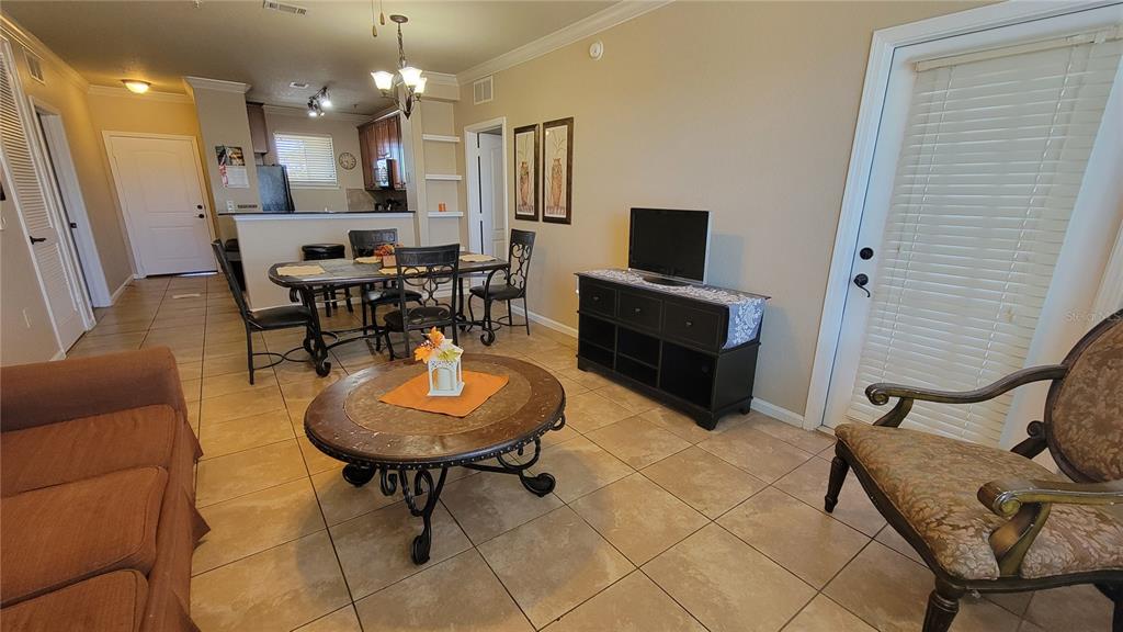 A living room and dining area with tile floors, a round coffee table, and furniture — 914 CHARO PARKWAY UNIT 123, DAVENPORT, FL