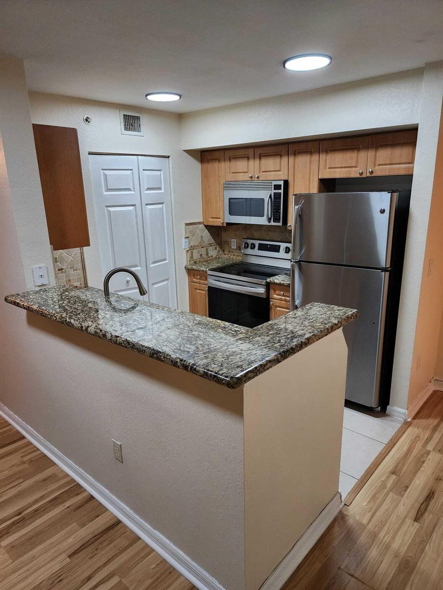 A kitchen with granite countertops, stainless steel appliances, and light wood cabinets — 6777 Heritage # 1208, Boynton Beach FL 33437, BOYNTON BEACH, FL