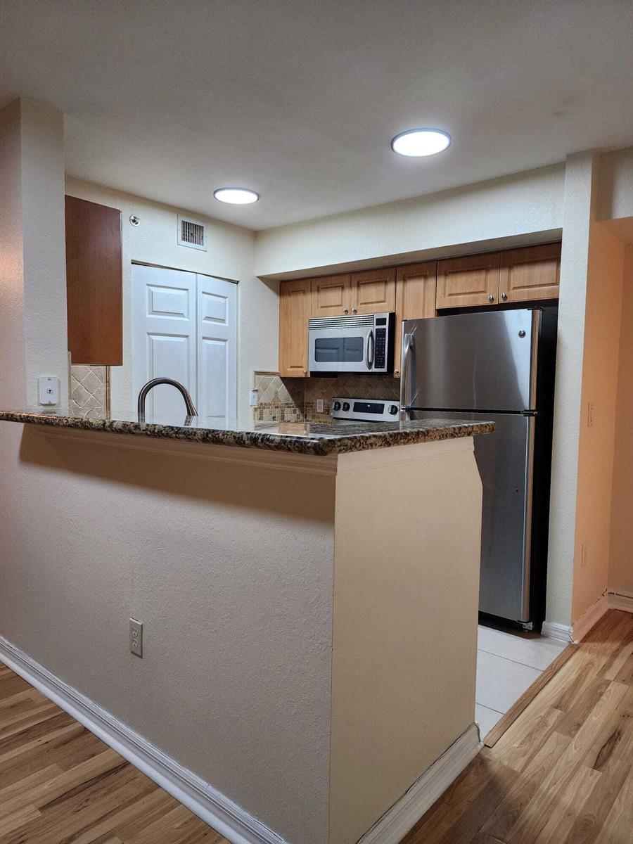 A kitchen with granite countertops, stainless steel appliances, and light wood cabinets — 6777 Heritage # 1208, Boynton Beach FL 33437, BOYNTON BEACH, FL