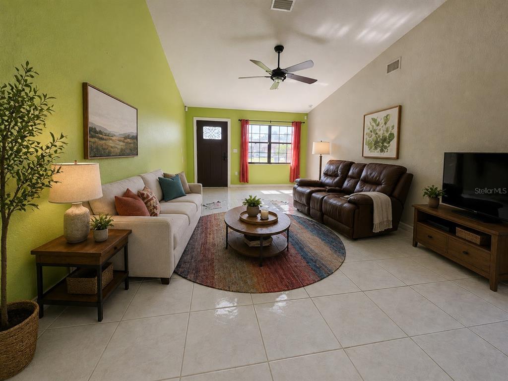 A bright green wall highlights this open-concept dining area with tile flooring and a ceiling fan — 4760 NE 28TH TERRACE, OCALA, FL