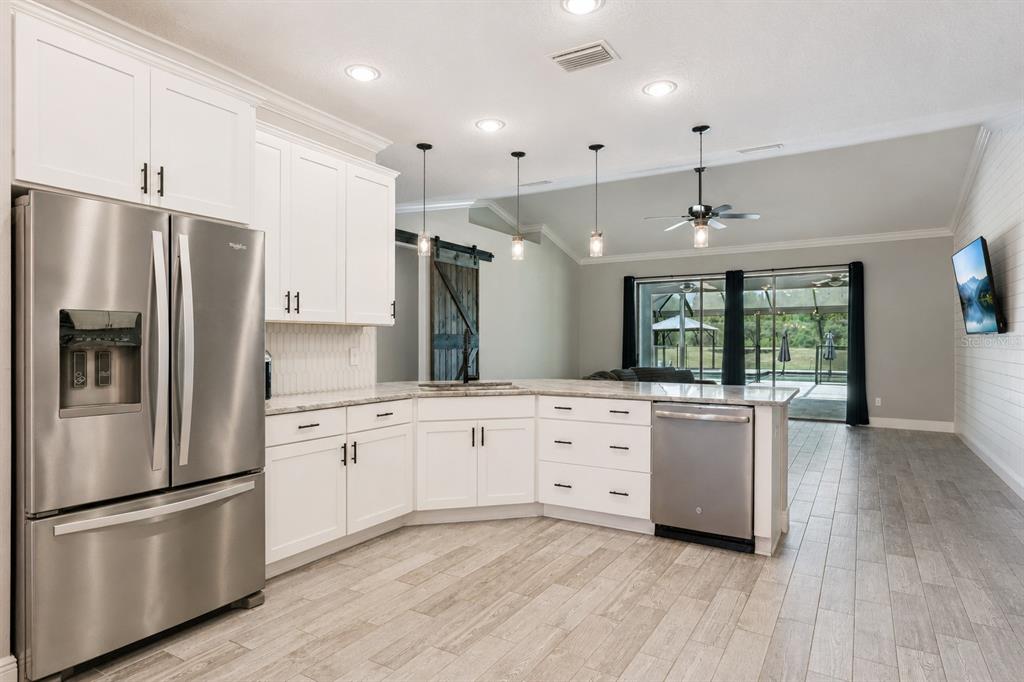 A kitchen with white cabinets, stainless steel appliances, and wood-look tile flooring — 18145 GREAT BLUE HERON DRIVE, GROVELAND, FL