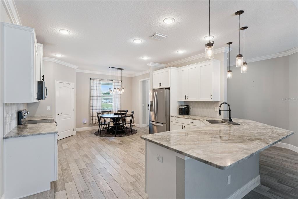 A kitchen with white cabinets, granite countertops, and a dining area with a round table — 18145 GREAT BLUE HERON DRIVE, GROVELAND, FL