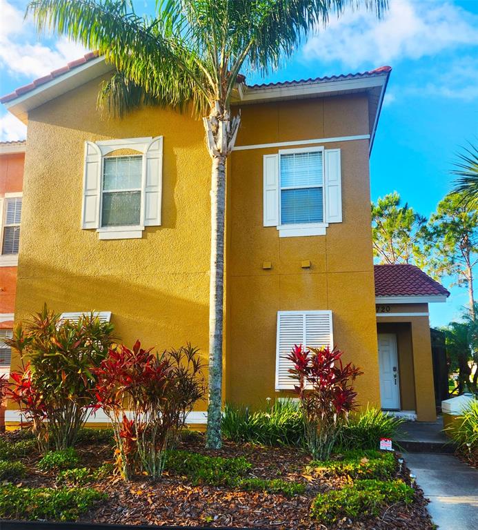 A two-story yellow stucco house features white shutters, a palm tree, and a front entrance — 4720 VERO BEACH PLACE, KISSIMMEE, FL