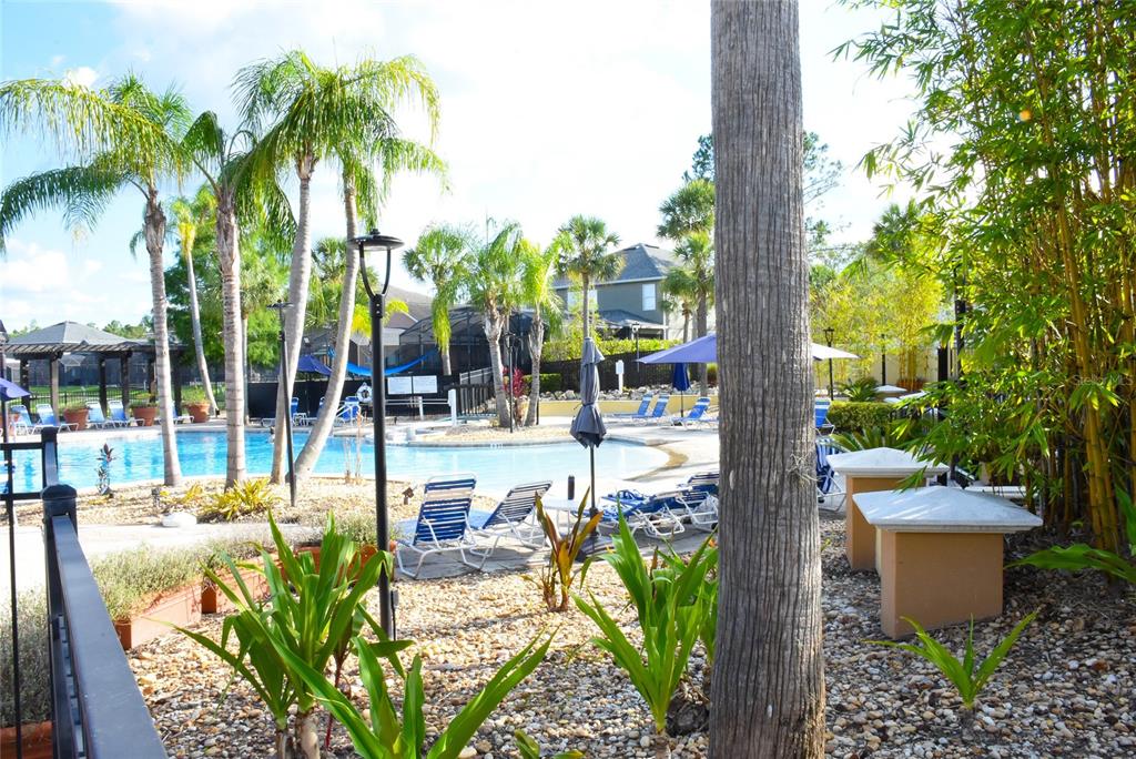 A swimming pool area features lounge chairs, palm trees, and a gravel landscape — 4720 VERO BEACH PLACE, KISSIMMEE, FL